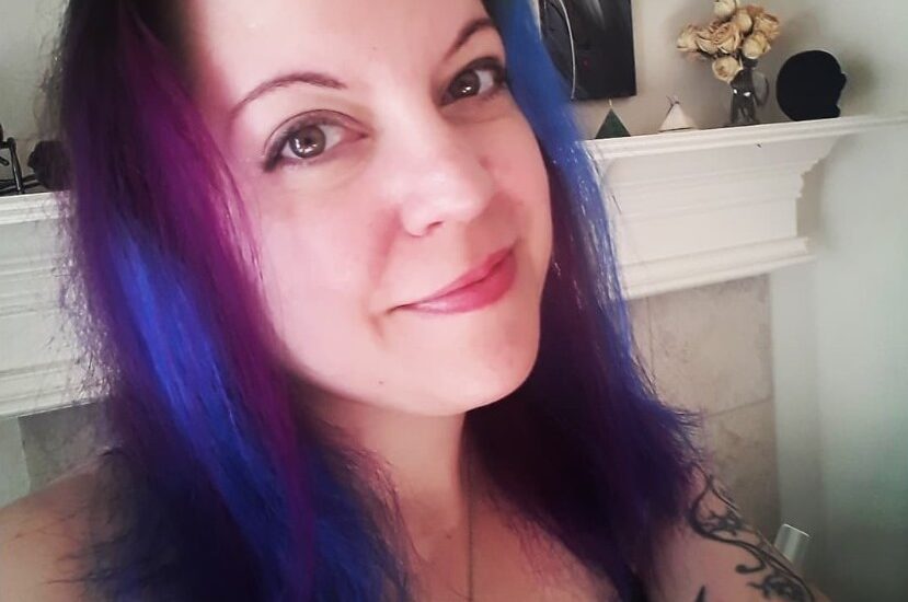 Woman with colorful hair smiling indoors.