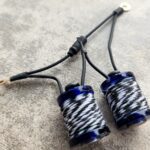 Close-up of two blue and white fishing rod guides on a gray surface.