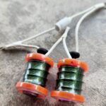 Close-up of green and orange fishing line spools with attached hooks.