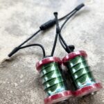 Two green fishing line spools with red tops on a concrete surface.