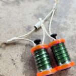 Close-up of a small, green and orange fishing line spooler tool.