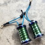 Two green coils with blue wires on a gray surface.