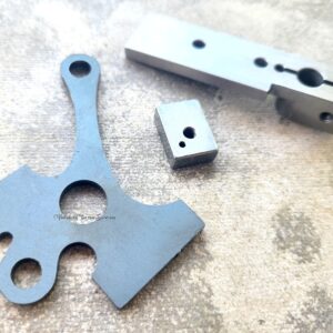 Three metallic machine components on surface.