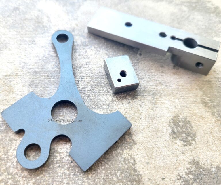 Three metallic machine components on surface.