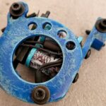 Close-up of a blue tattoo machine with a visible coil inside.