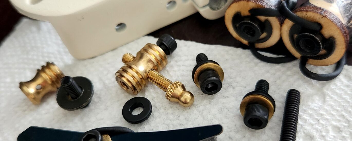 Disassembled mechanical parts with screws and fittings on a dark surface.