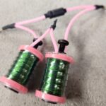 Close-up of green and pink fishing reels with attached lines.