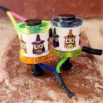 Two colorful drink holders with owl designs on a marble surface.