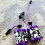 Close-up of black and purple stringed maracas with skull designs.