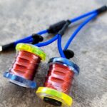 Close-up of two fishing reels with red fishing lines on a blue surface.