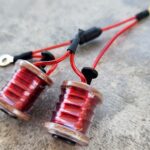 Close-up of two red electromagnetic coils with attached black and red wires.