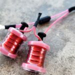 Close-up of pink and red fishing line spools on a gray surface.