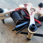 Close-up of a drone's motor and wiring assembly on a textured surface.