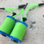 Close-up of green and blue skipping rope handles on concrete.