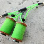 Close-up of green thread spools on a rough surface.