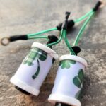 Two small binoculars with a green leaf pattern and black straps.