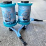 Two blue fishing reels placed on a concrete surface.