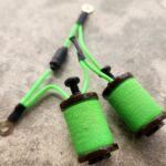 Close-up of green thread spools and bobbins on a surface.