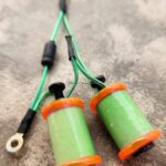 Close-up of two green electrical coils with orange bases and attached wires.