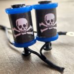 Tattoo machine with skull and crossbones design on ink caps.
