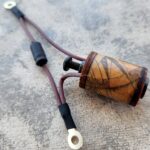 Handcrafted wooden smoking pipe with a leather strap on a concrete surface.
