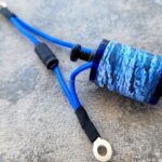 Blue electrical wire with a ring terminal and a coiled section.