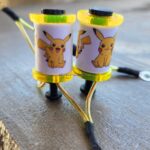 Two Pikachu-themed earbuds with yellow accents on a table.