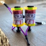 Two small cylindrical devices with colorful wires on a wooden surface.