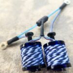 Two blue and white string spools with handles on a surface.
