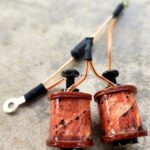 Close-up of two copper wire coils with attached black cables.