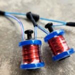 Close-up of three small spools of red wire with blue rims.