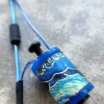 A blue fishing rod with a painted reel featuring ocean waves and a whale.