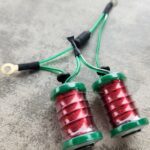 Close-up of two red and green coils with green wires attached.