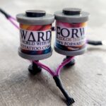 Two small tattoo ink caps labeled with different ink colors on a surface.
