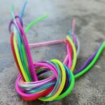 A colorful knot made from intertwined plastic strings on a gray surface.