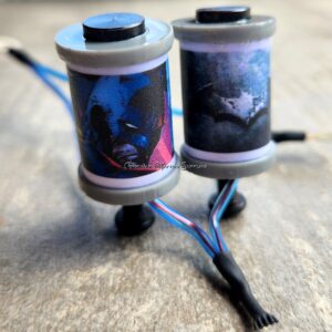 Two tattoo machine coils with dark-themed artwork attached.