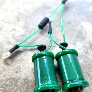 Two green electrical coils connected by wires on a concrete surface.