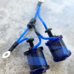 Two blue electrical coils with attached wires on a concrete surface.