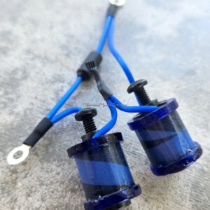 Two blue electrical coils with attached wires on a concrete surface.