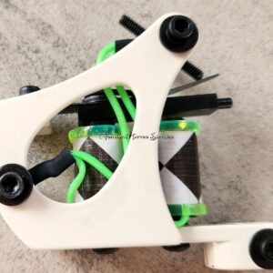 Close-up of a white and green skateboard truck with black wheels on concrete.