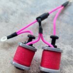 Close-up of two red electrical coils with pink wires connected.