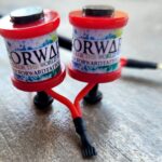 Two red fishing reels labeled 'Norway' on a textured surface.