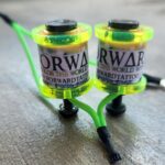 Two vibrant green and yellow fishing reels with Orwar branding on a wooden surface.