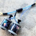 A pair of fishing reels with blue lines on a textured surface.