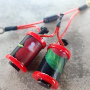 Close-up of two small colorful coil devices connected by red wires.
