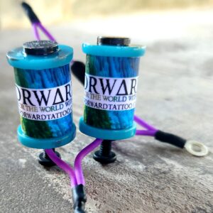 Two blue tattoo machine coils with purple wires on a white surface.