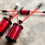 Close-up of red anodized bike brake cable ends on a gray surface.