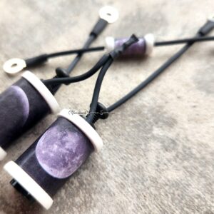 Close-up of purple crystal pendants on black cords.