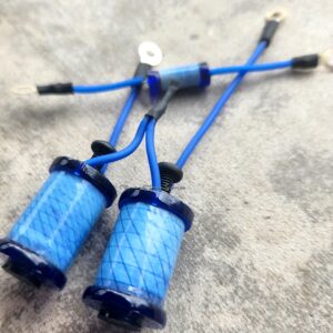 A pair of blue slingshots with wrapped handles on a concrete surface.