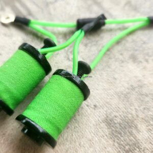 Close-up of vibrant green thread spools connected by matching thread.
